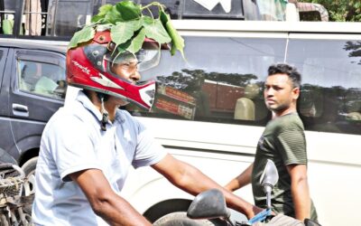 バイクに乗った男性が、涼をとるためにヘルメットの上にガジュマルの葉を置いている。