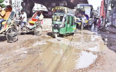 交通量の多い幹線道路の水浸しの穴の中を走る車