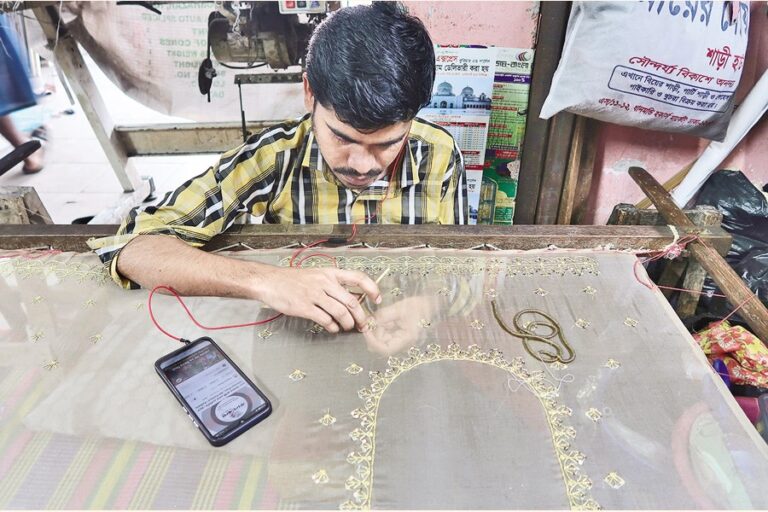 職人がドレスに複雑な縫製デザインを施している