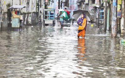 フサイニ・ダラン地区の水浸しの道路を渡る女性