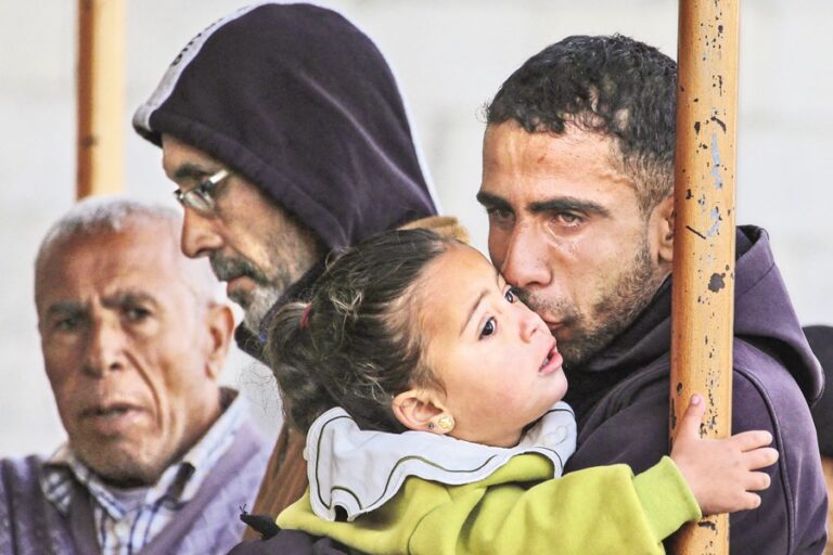 パレスチナ人の弔問客が赤ん坊の娘にキスをしながら涙を流す