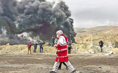 イラン赤新月社の女性会員が煙の近くを歩く