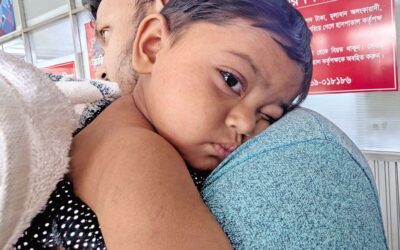 麻疹に感染した子供が父親の肩にもたれかかっている。