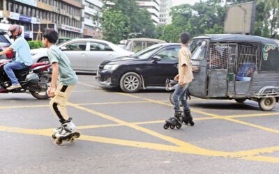 カルワンバザール交差点の交通量の多い道路で、2人の少年がスケートをしている。