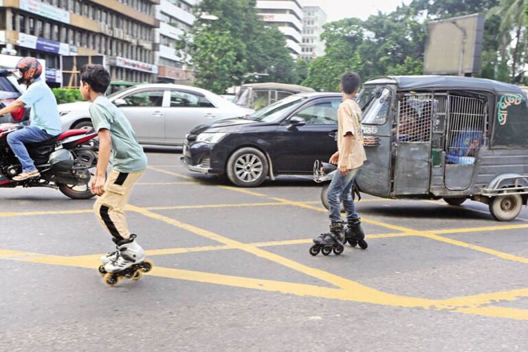 カルワンバザール交差点の交通量の多い道路で、2人の少年がスケートをしている。