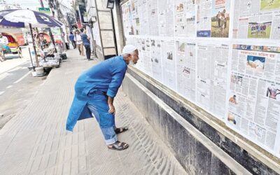 高齢者が身を乗り出し、壁新聞を熱心に読んでいる。